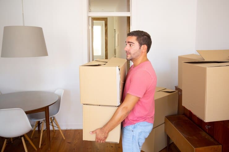 focused-man-carrying-carton-boxes-into-new-apartment