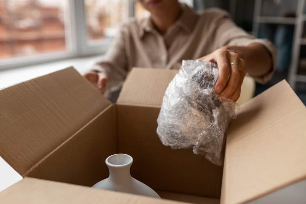 a person placing a fragile glassware in a moving box